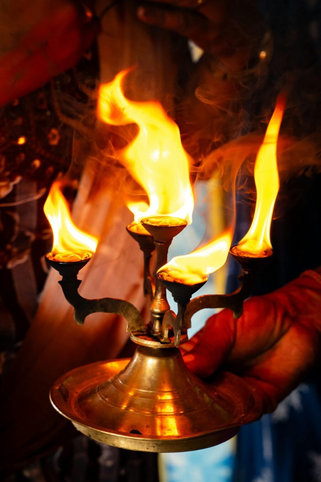 Hands holding a lit brass aarti lamp